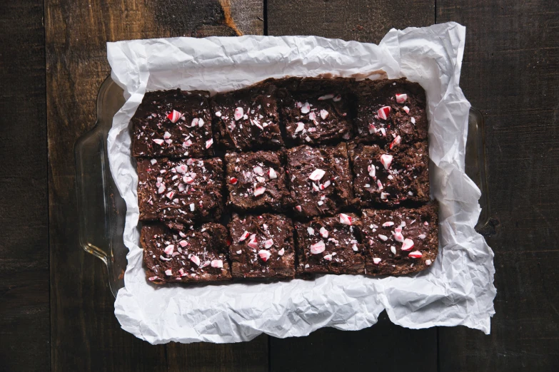 a chocolate brownie on paper is next to some milk