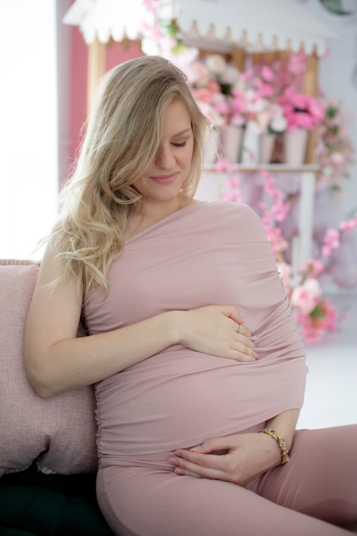 a woman sits in a chair with a feeding baby