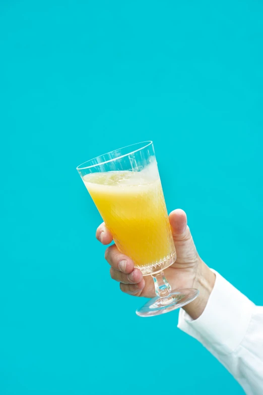 a person is holding a glass with orange juice in it