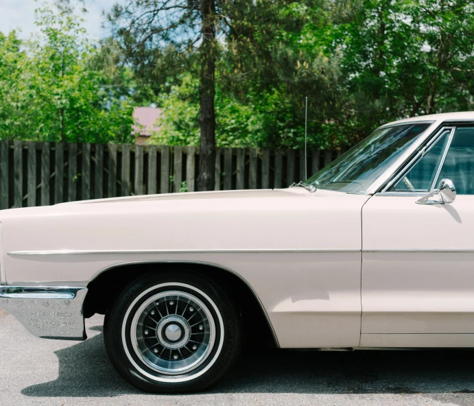 old car parked in the street with trees in the background