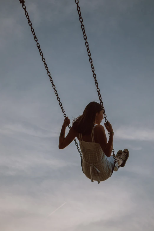 a woman riding a swing in the sky