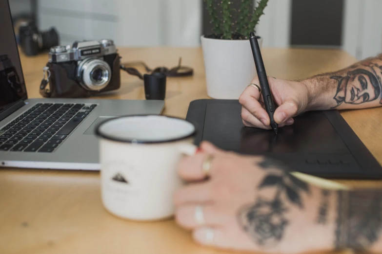 person writing on notebook at the desk next to laptop