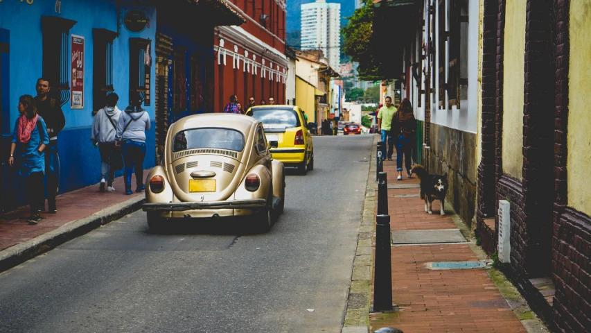 a white and yellow bug driving down a street next to other cars