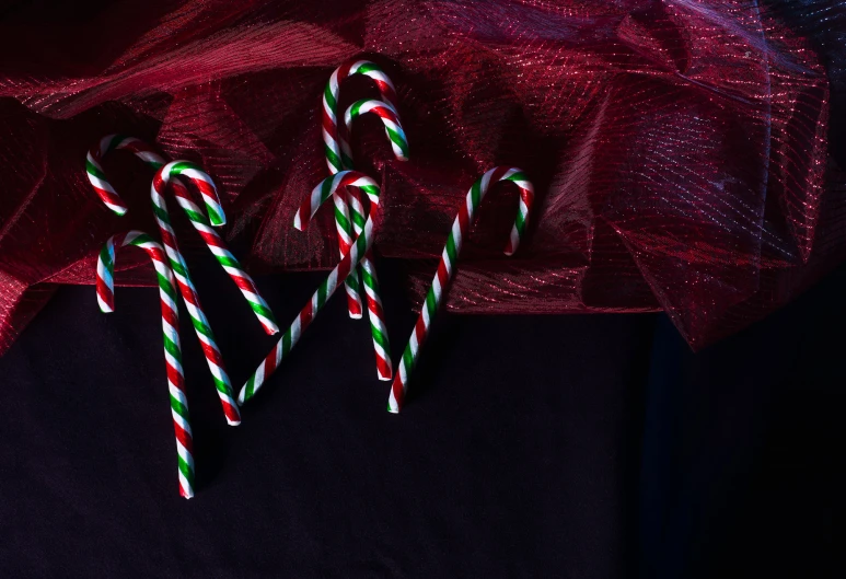 two candy canes sitting in front of a black table cloth