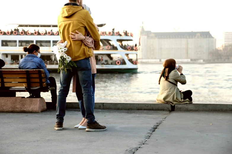 people sit and watch as they talk by the water