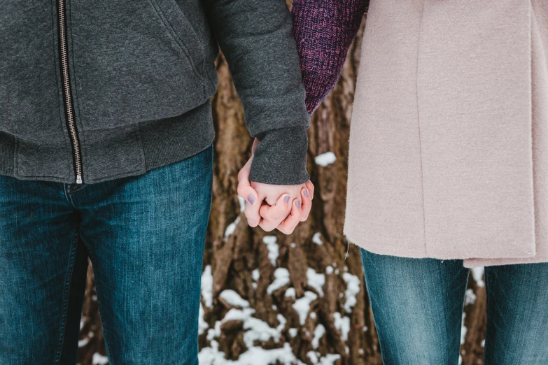 a couple holding hands walking through the snow