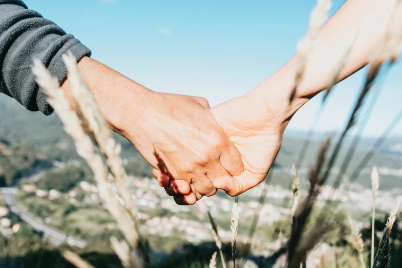 a close up of two people holding hands in the grass