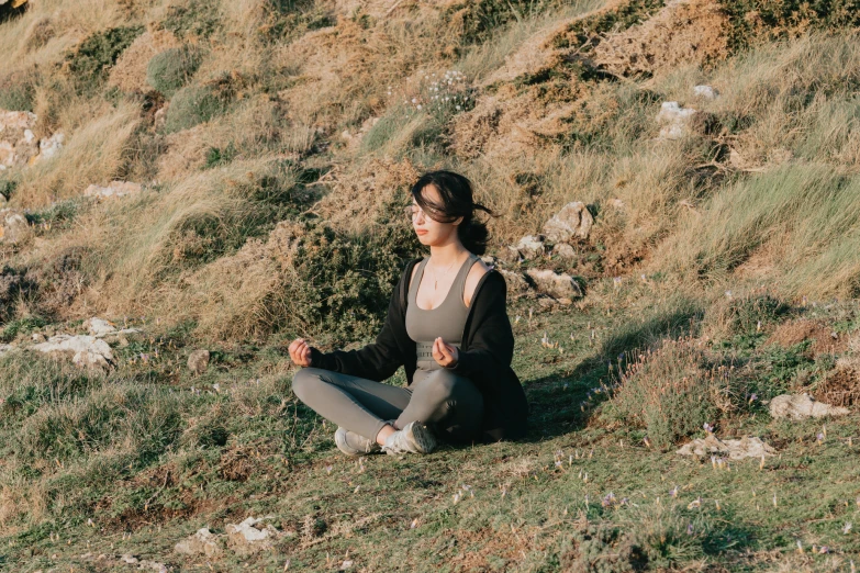 a woman sitting in a grass field on her knees