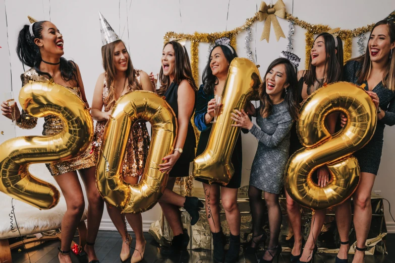 a group of women posing with giant golden numbers