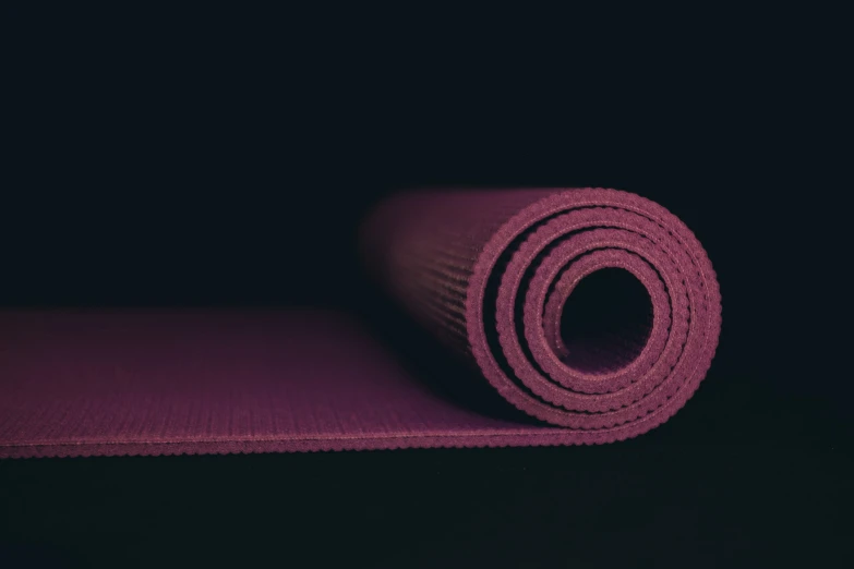 the purple yoga mat is rolled up on the floor