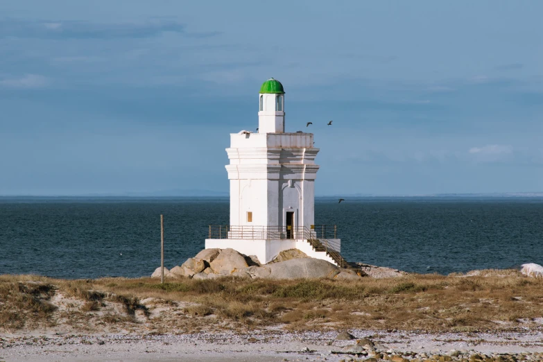 the green top on this tower looks over the ocean