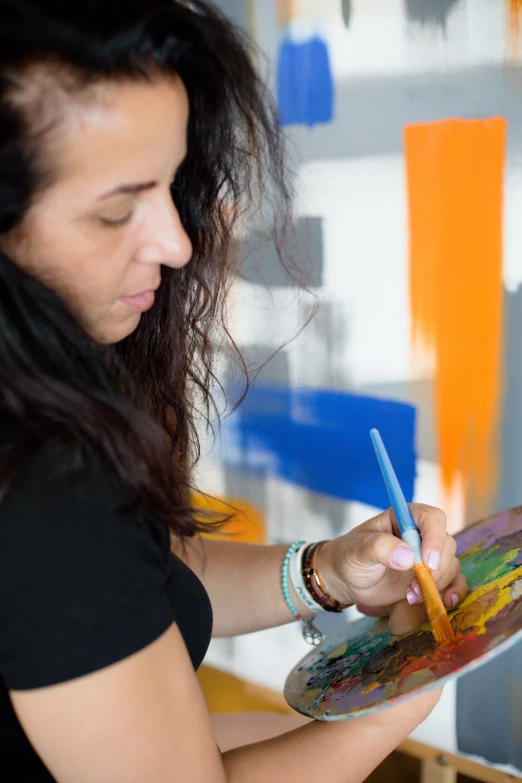 a woman holding a paintbrush and a paint palette