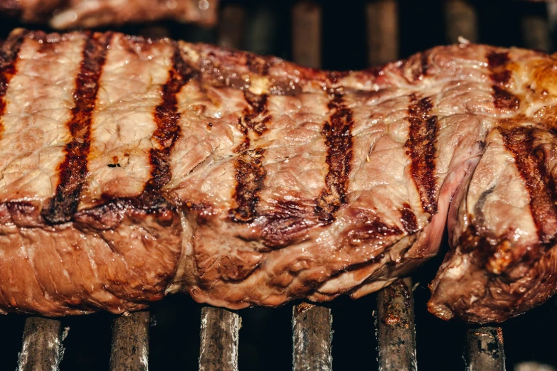 pieces of meat on a grill cooking over  coals