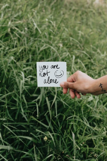 someone holding a note with the word you are not alone