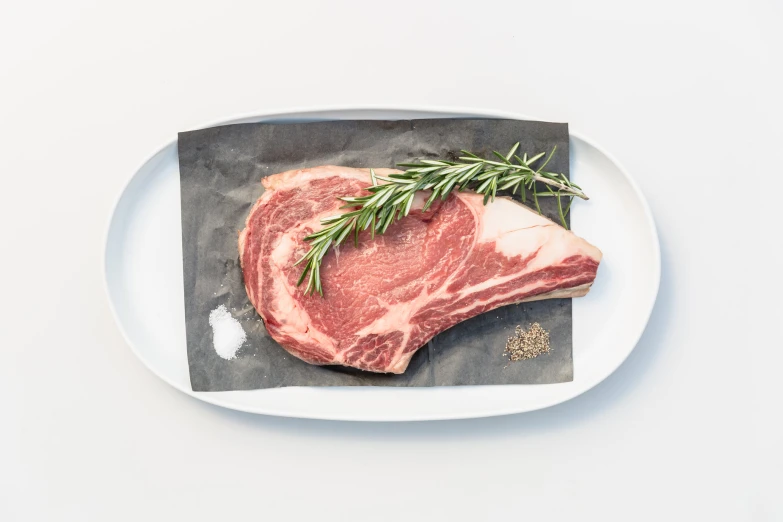 a piece of steak on a plate with rosemary on the top