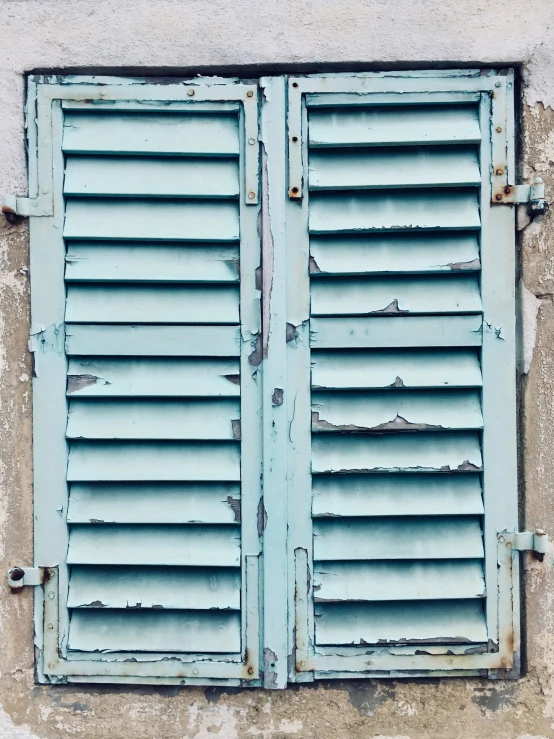 blue window with closed shutters sits on an old building