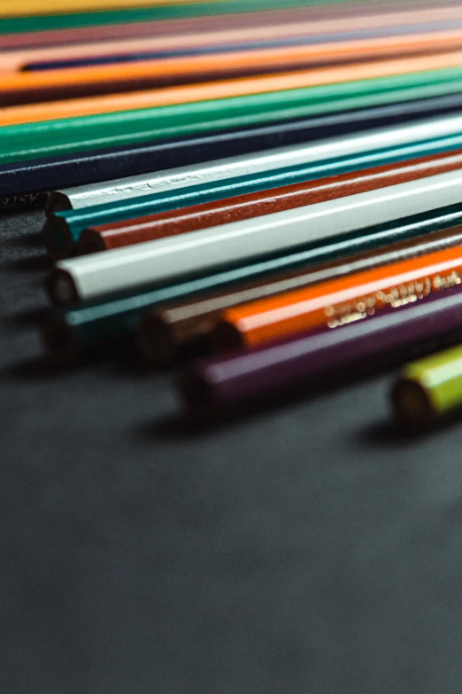 close up of various colored pencils arranged on black surface