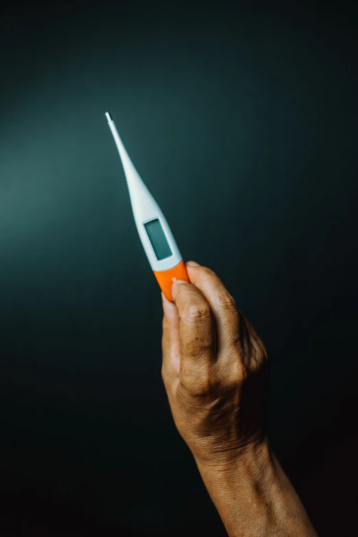 someone holds up a small electronic thermometer