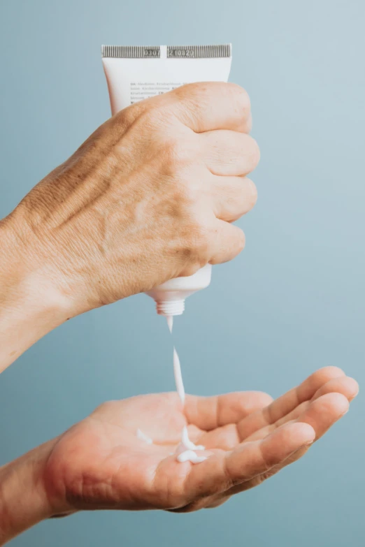 a person's hand is pouring lotion onto someones hair