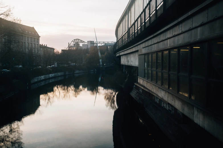 the sun sets on an urban setting that looks like a river