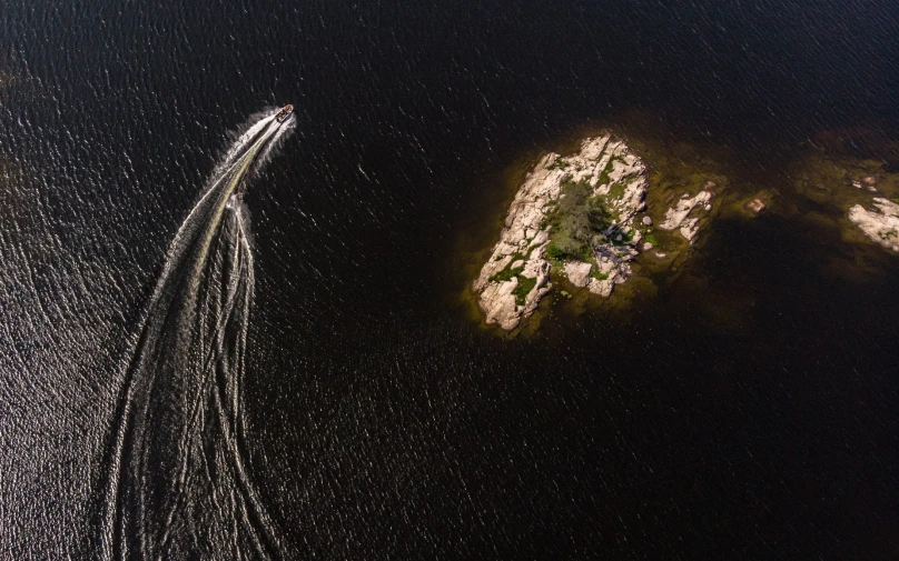 an aerial view of an ocean boat coming towards the land