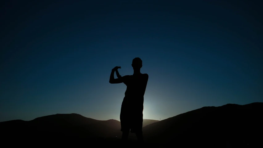 a man standing on top of a hill at sunset