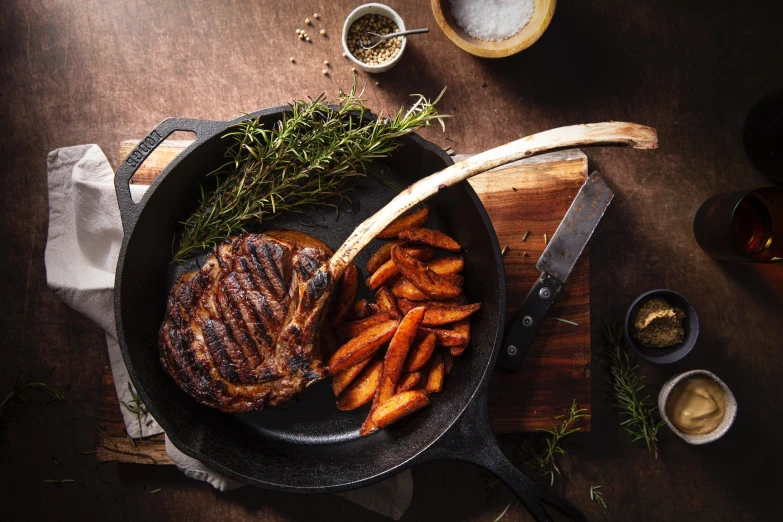 steak, fries and carrots in a frying pan