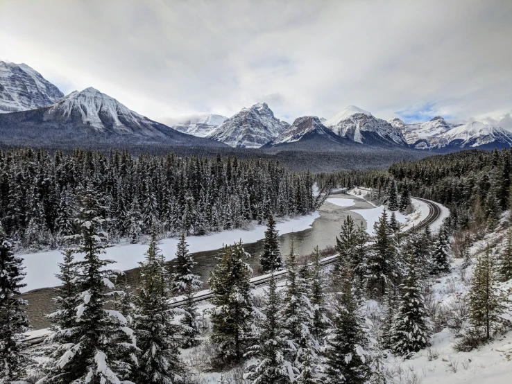 the landscape has snow, pine trees, and mountains in it