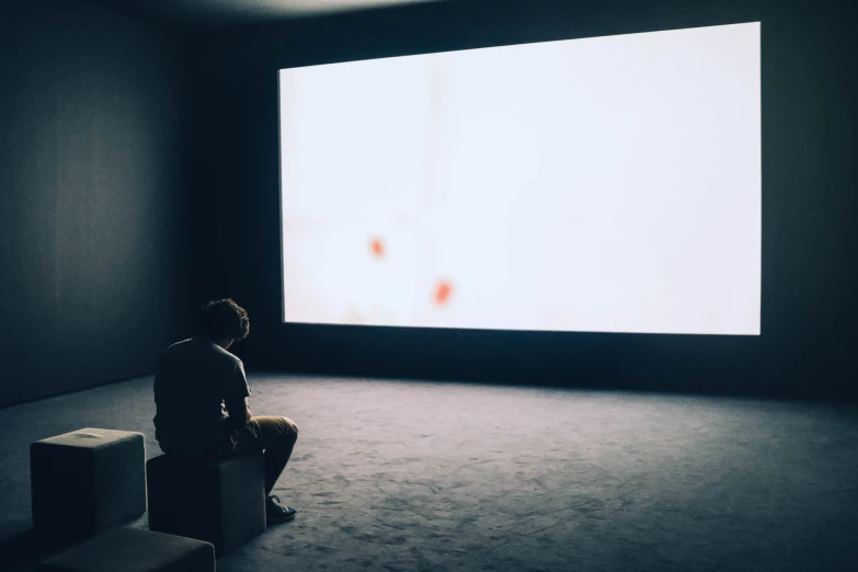 a man sits alone in front of the television screen