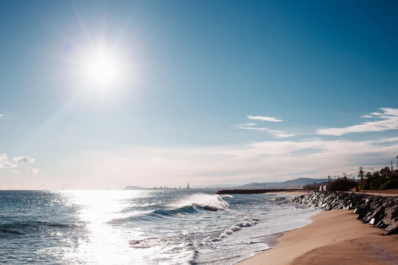 a view of a beach with a bright sun coming over it