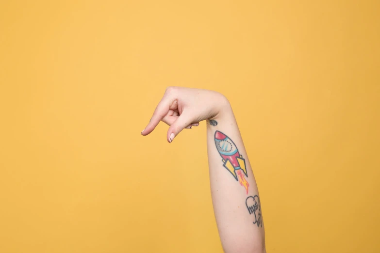 a person with a tattoo holds their arm in the air
