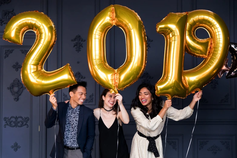 people hold up golden balloons at the end of a new year's eve celetion