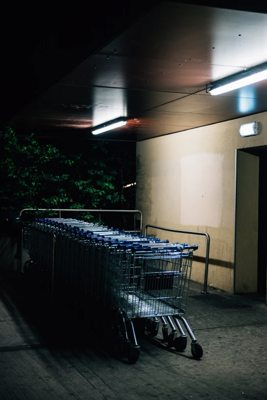a pile of blue shopping carts parked by an open building