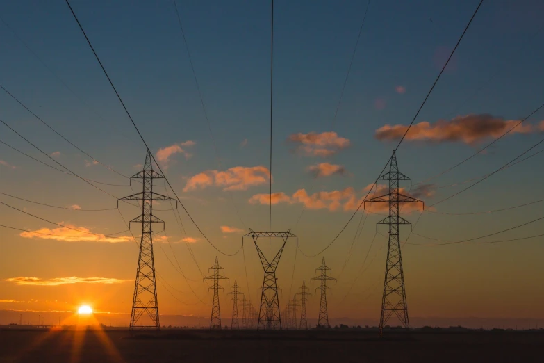 the sun is setting behind high voltage power poles