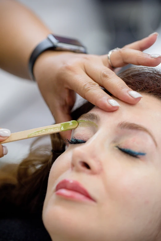 a woman doing eyeliners on her forehead as she is getting her eyebrows done