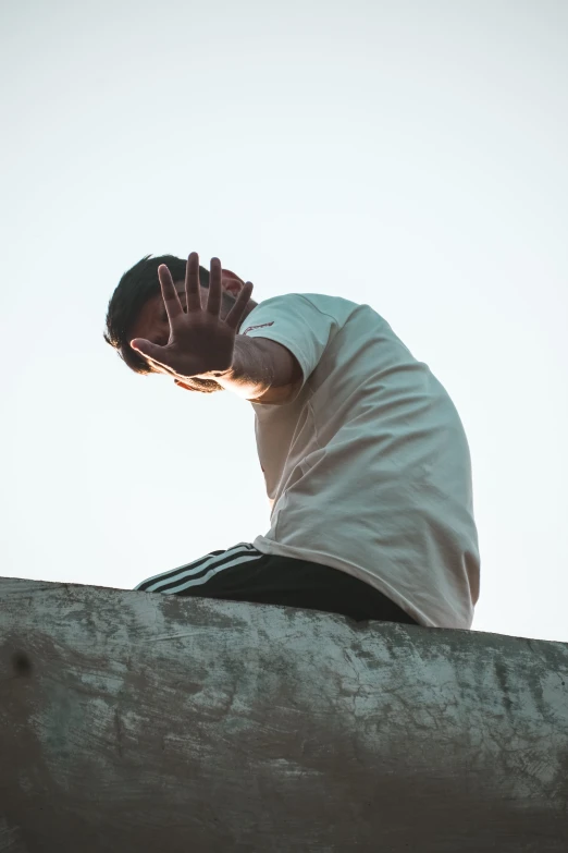 a man sitting on a ledge with his hands in the air