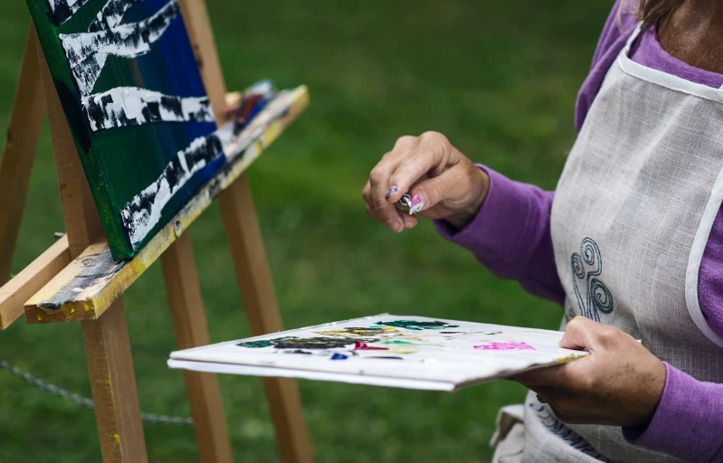 woman painting on an easel with a black and white cat on it