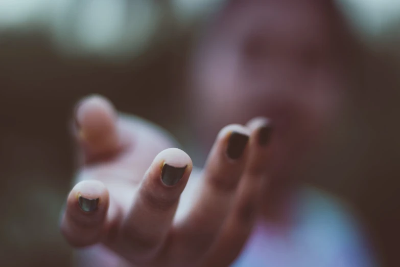 a blurry image of a woman's hand with black and gold nail polish