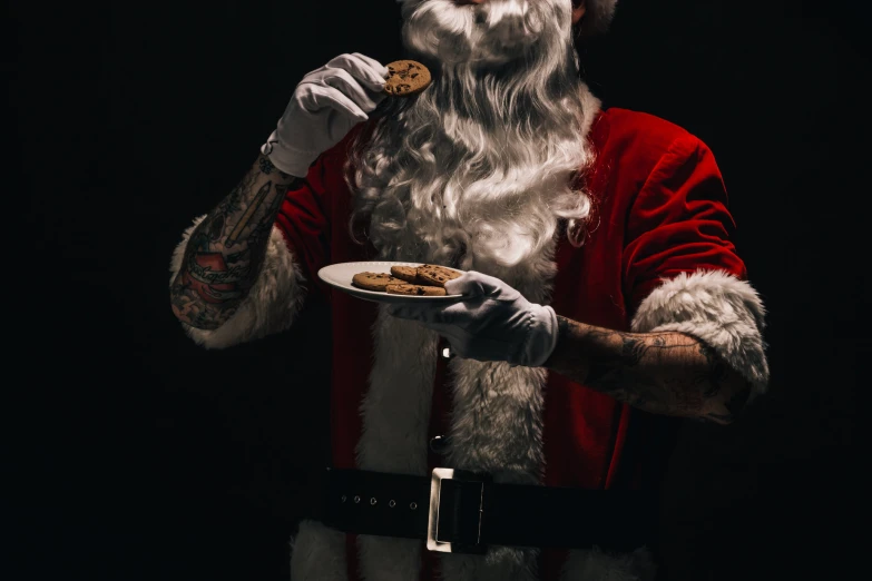 a man dressed in santa claus clothing and hat holding a plate of food