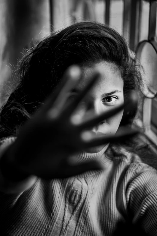 an image of woman looking out the window with hand near window