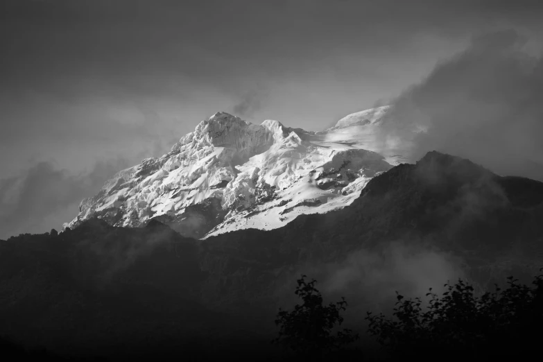 the snow capped mountains are surrounded by dark clouds