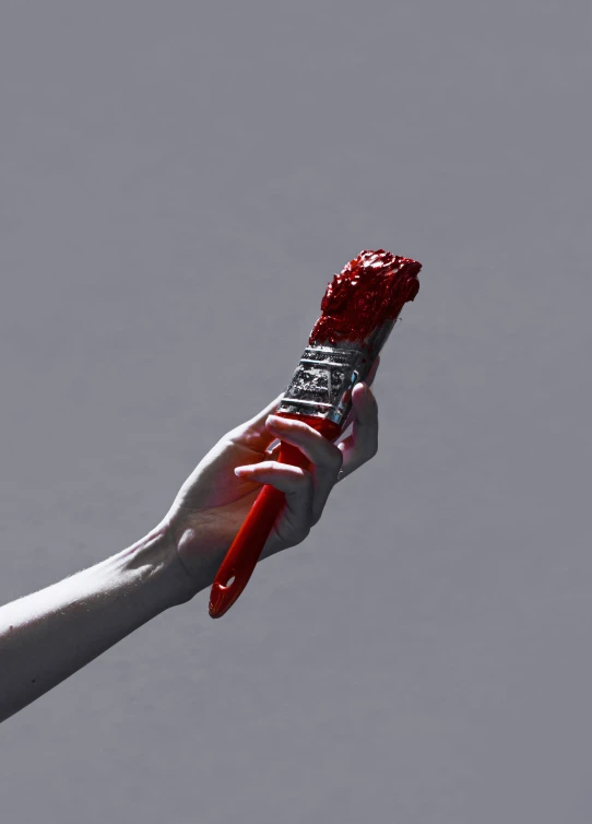 a woman holds up a red handmade tooth brush