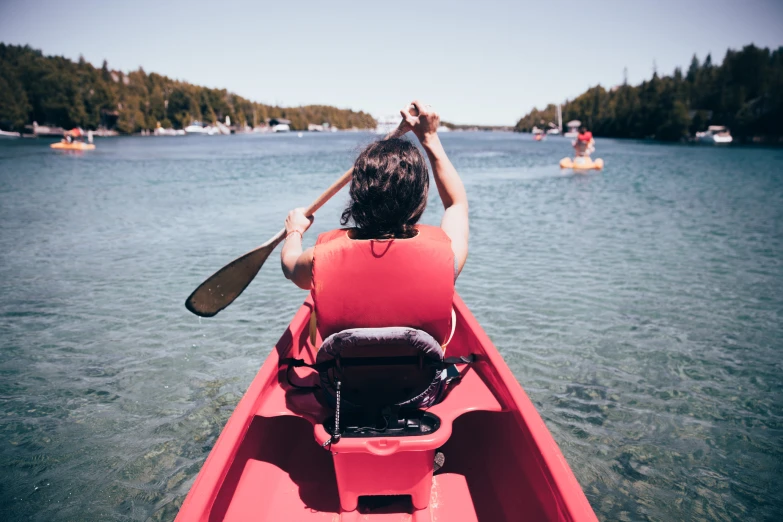 a person paddling in a canoe with paddles on a lake