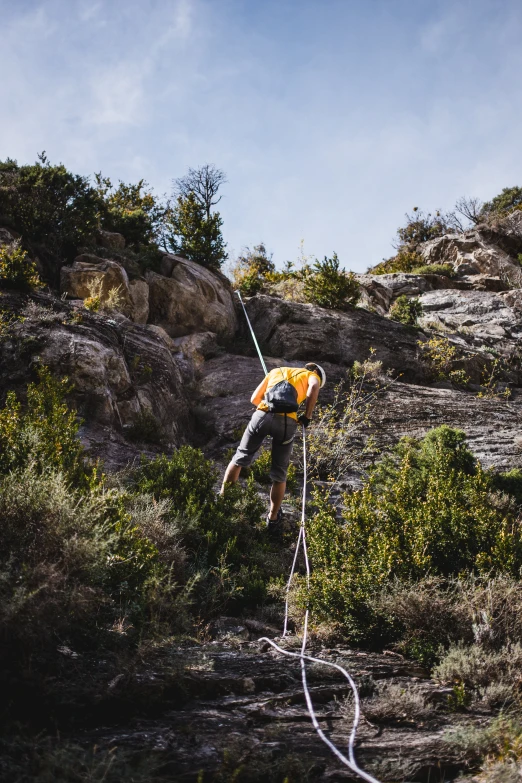 a man walking on a steep hill while using a rope to go