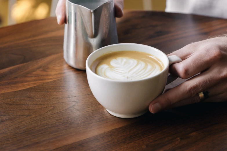 someone holding a coffee cup on a wooden table