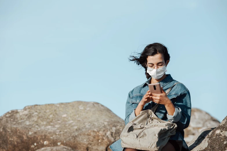 a woman is sitting on a rock with a face mask