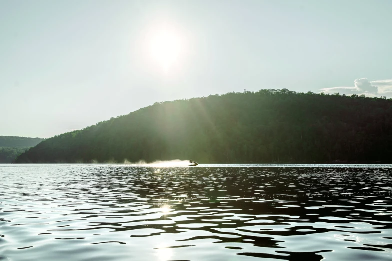 a boat traveling on the water next to a mountain