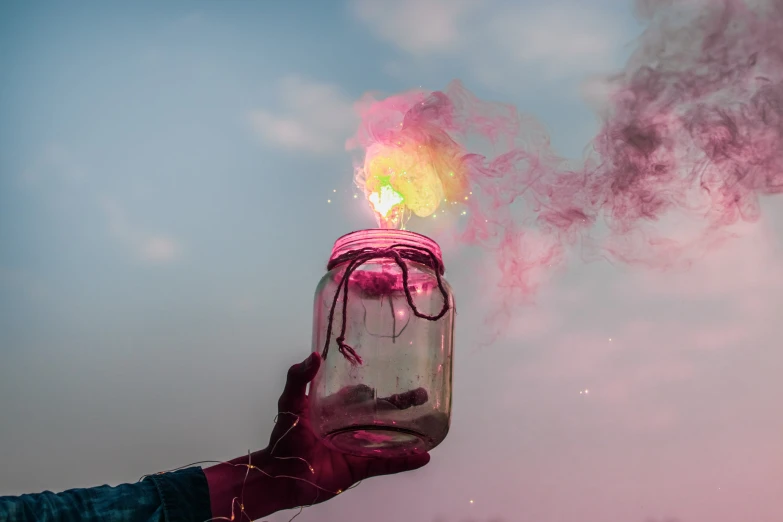 a person holding a glass bottle with smoke coming out