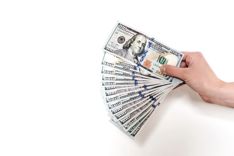 a man holding money up on a white wall