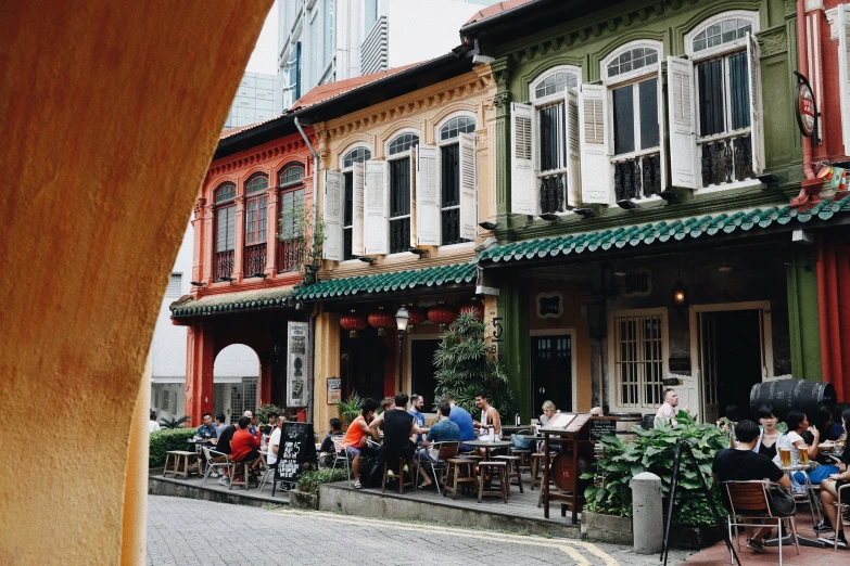 people sitting outside a restaurant on the side of a street